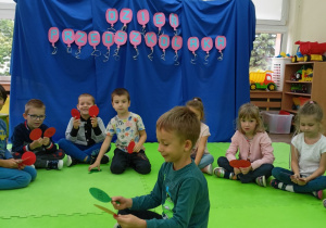 Gabryś siedzący w kole podczas zabawy z lizakami.