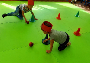 Dzieci turlają jablka slalomem między pachołkami