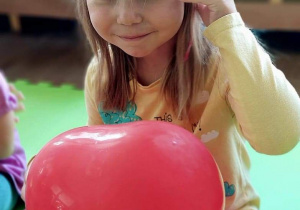 Dziewczynka trzyma w dłoni czerwony balon