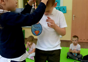 Dziewczynka zakłada chłopcu medal na szyję