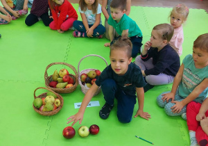 Chłopiec układa tyle jabłek, ile sylab słyszy w wyrazie "owoce"