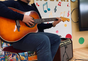 Pan Jacek prezentuje gitarę akustyczną.