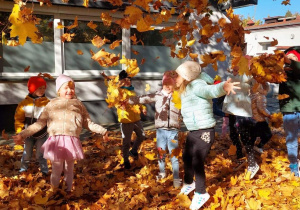 Dzieci rzucają w górę kolorowymi liśćmi