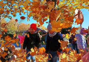 Dzieci bawią się wśród jesiennych liści