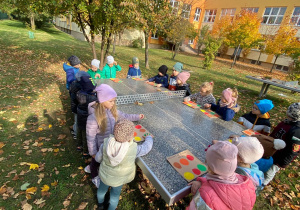 Dzieci stoją przy planszach z jesiennymi kolorami.