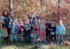 Dzieci pozują do zdjęcia na tle jesiennego lasu