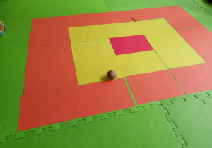 Ziemniak leżący na planszy ułożonej z kolorowych kartonów.
