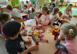 Dzieci przy stolikach podczas pracy plastycznej.
