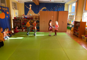 Dzieci pokonują dyniowy tor przeszkód z obręczami hula hop.