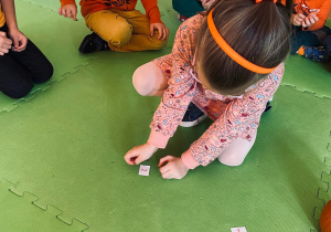 Przedszkolaki bawią się w zabawę matematyczną z użyciem pestek dyni.