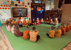 Przedszkolaki siedzą w kółeczku podczas zabawy.
