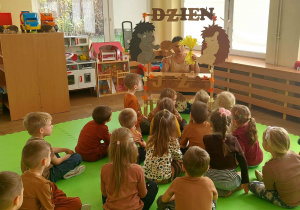 Dzieci oglądają teatrzyk wystawiany przez nauczycielkę