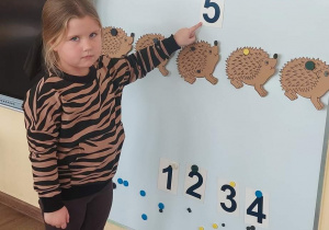 Dziewczynka wskazuje na cyfrę, która odpowiada ilości przeliczanych elementów