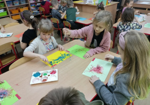 Dzieci przy stoliku podczas malowania muzyki.