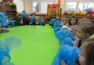 Dzieci siedzące w kole z folią w dłoniach.