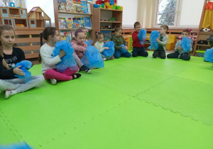 Dzieci siedzące w kole z folią w dłoniach podczas zabawy rytmicznej.