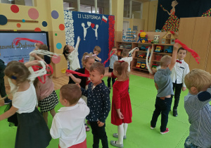 Przedszkolaki podczas zabawy ruchowej machają paskami bibuły w barwach narodowych.