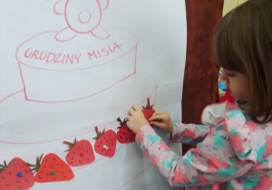 Dziewczynka dekoruje tort dla misia.