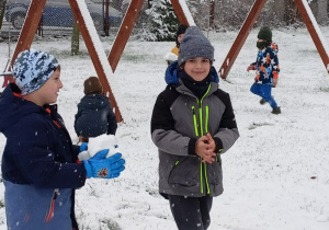 Chłopcy biegający i lepiący śnieżne kulki.