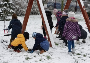 Dzieci toczą kulki ze śniegu.