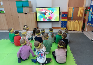 Dzieci słuchająi oglądają ilustrowaną piosenkę o kredkach