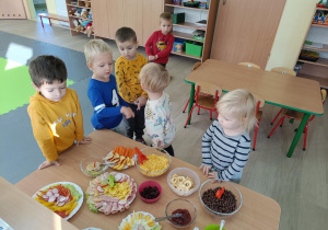 stół z różnymi potrawami , dookoła stoją dzieci