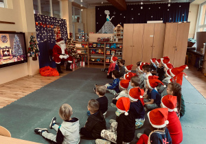 Święty Mikołaj rozmawia z dziećmi.
