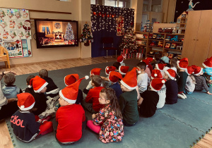 Przedszkolaki oczekują na Świętego Mikołaja przy dźwiękach nastrojowej, świątecznej muzyki.