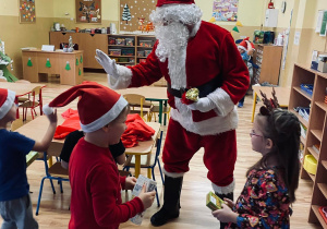 Święty Mikołaj przybija piątkę z dziećmi.