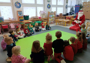 Dzieci siedzą na dywaniei rozmawiają z Mikołajem