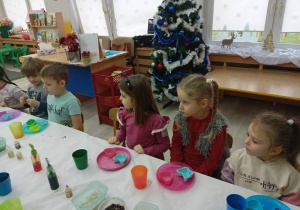 Dzieci przy stole słuchające wskazówek prowadzącego.