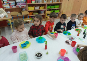 Dzieci przy stole oglądają przygotowane materiały.