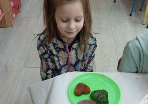Dziewczynka z zadowoleniem patrzy na swe mydełka w kształcie serca i sowy.