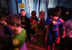 Dzieci w kolorowych przebraniach na sali karnawałowej.