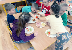 Przedszkolaki przygotowują kanapeczki na podwieczorek.