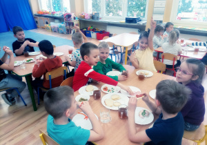 Przedszkolaki zjadają przygotowane przez siebie kanapeczki na podwieczorek.