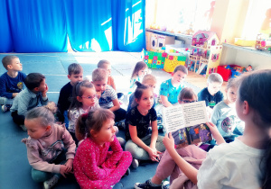 Przedszkolaki słuchają opowiadań czytanych przez pierwszoklasistki.