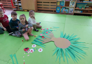 Dzieci nalepiają zrobione kwiaty