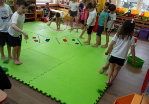 Dzieci podzielone na zespoły wykonują ćwiczenia gimnastyczne.