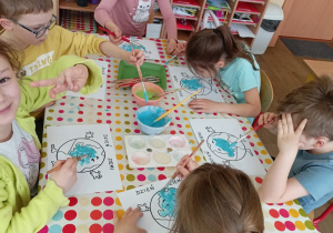 Grupa dzieci nanosi farby rosnące na swe obrazki.