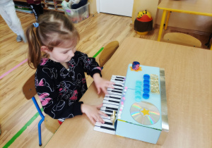 Dziewczynka naśladuje grę na keyboardzie.