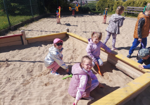 Dziewczynki bawią się w piaskownicy.