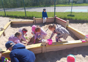 Dzieci bawią się w piaskownicy.