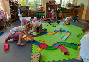 Dzieci zgodnie bawią się na dywanie. Brawo!