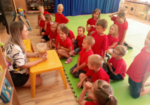 Dzieci z nauczycielką sprawdzają czy jabłka toną w wodzie.