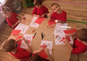 Przedszkolaki tworzą swoje jabłka, wyklejając kawałkami podartego papieru.