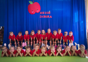 Dzieci pozują do zdjęcia pod napisem dzień jabłka.