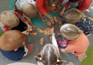 Dzieci układają puzzle dyniowe.