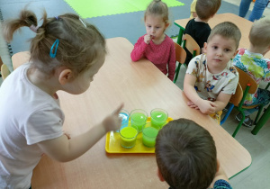 Dzieci przy stole porównują kolorową wodę.