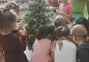 Dziewczynki dekorują świąteczne drzewko.
